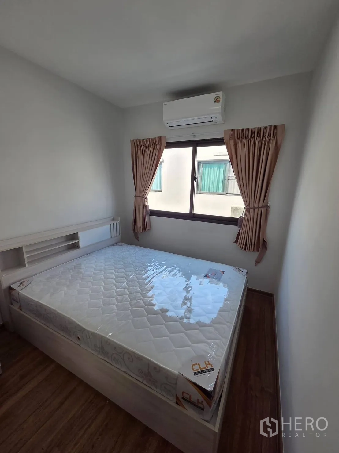 Townhouse for rent in Bang Phli, Samut Prakan - Compact bedroom with bed, window, and wall-mounted air conditioner.