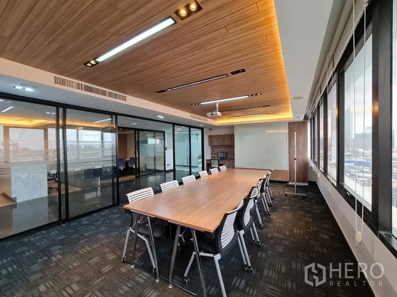 Office Space for rent in Bang Rak, Bangkok - Spacious boardroom with long table, projector, wood ceiling, and glass walls overlooking the city.