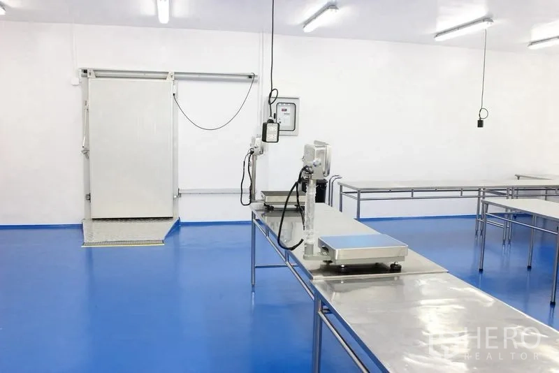 Factory for rent or sale in Krathum Baen, Samut Sakhon - Clean room with a sliding insulated door and stainless workbenches on a blue floor.