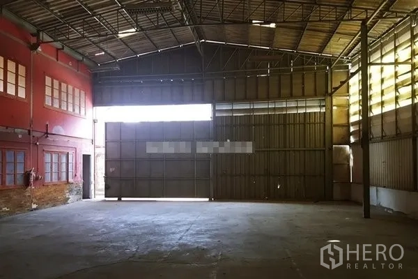 Warehouse for rent in Suan Luang, Bangkok - Spacious warehouse interior featuring a steel truss roof, high clearance and large sliding loading doors.