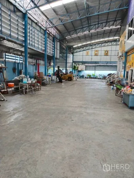 Warehouse for sale in Sai Noi, Nonthaburi - Clear-span warehouse interior with high steel roof, side ventilation panels, and wide concrete floor.