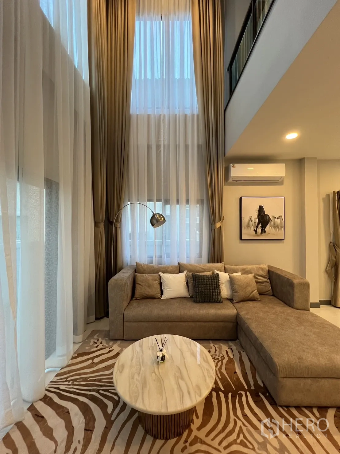 Detached House for rent or sale in Bang Phli, Samut Prakan - Double-height curtains and upper-level balcony above the living area.