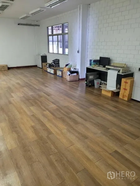 Warehouse for rent in Phra Khanong, Bangkok - Bright office room inside the warehouse with wood-look flooring, white brick walls, and windows.