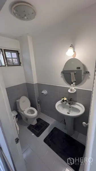 Townhouse for rent or sale in Khlong Toei, Bangkok - Clean guest bathroom with pedestal sink, mirror and ventilation window.