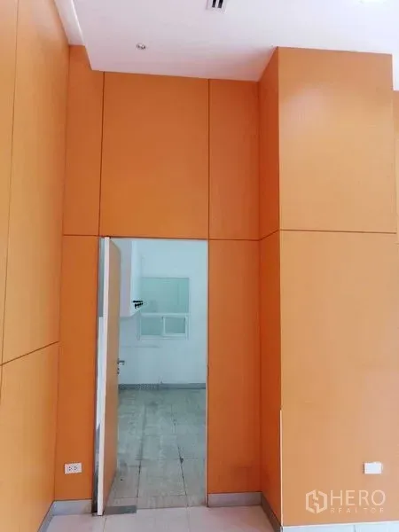 Office Space for rent in Pathum Wan, Bangkok - Interior with orange wall panels and a doorway leading to a back office zone.