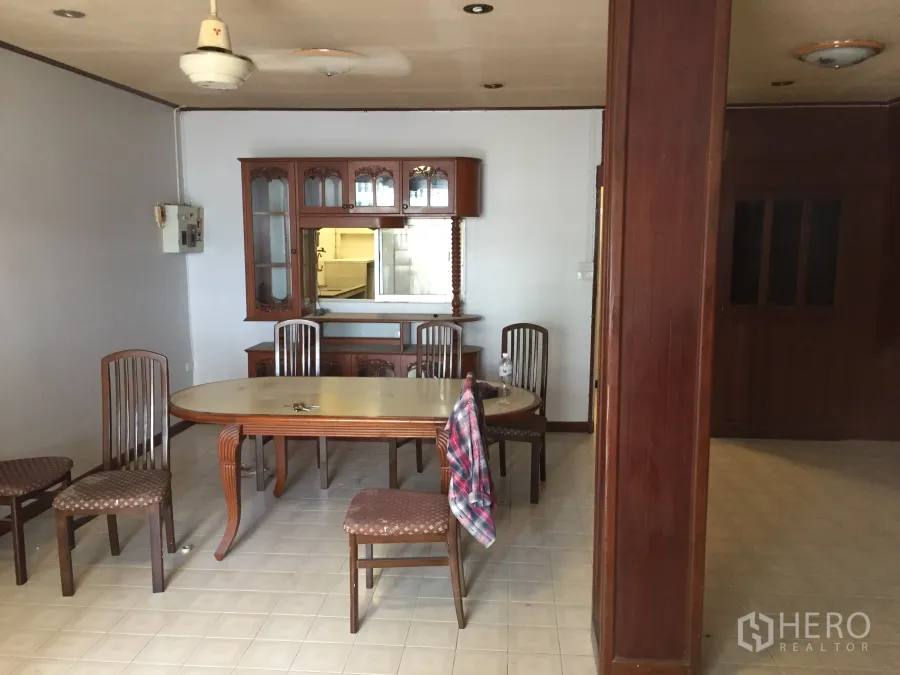 Townhouse for rent in Khlong Toei, Bangkok - Dining area with wooden table and chairs, built‑in glass cabinet, tiled floor and ceiling fan.