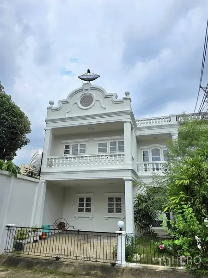 Townhouse for sale in Khlong Toei, Bangkok - White two-storey corner townhouse in Khlong Toei with balcony, gated carport and greenery.