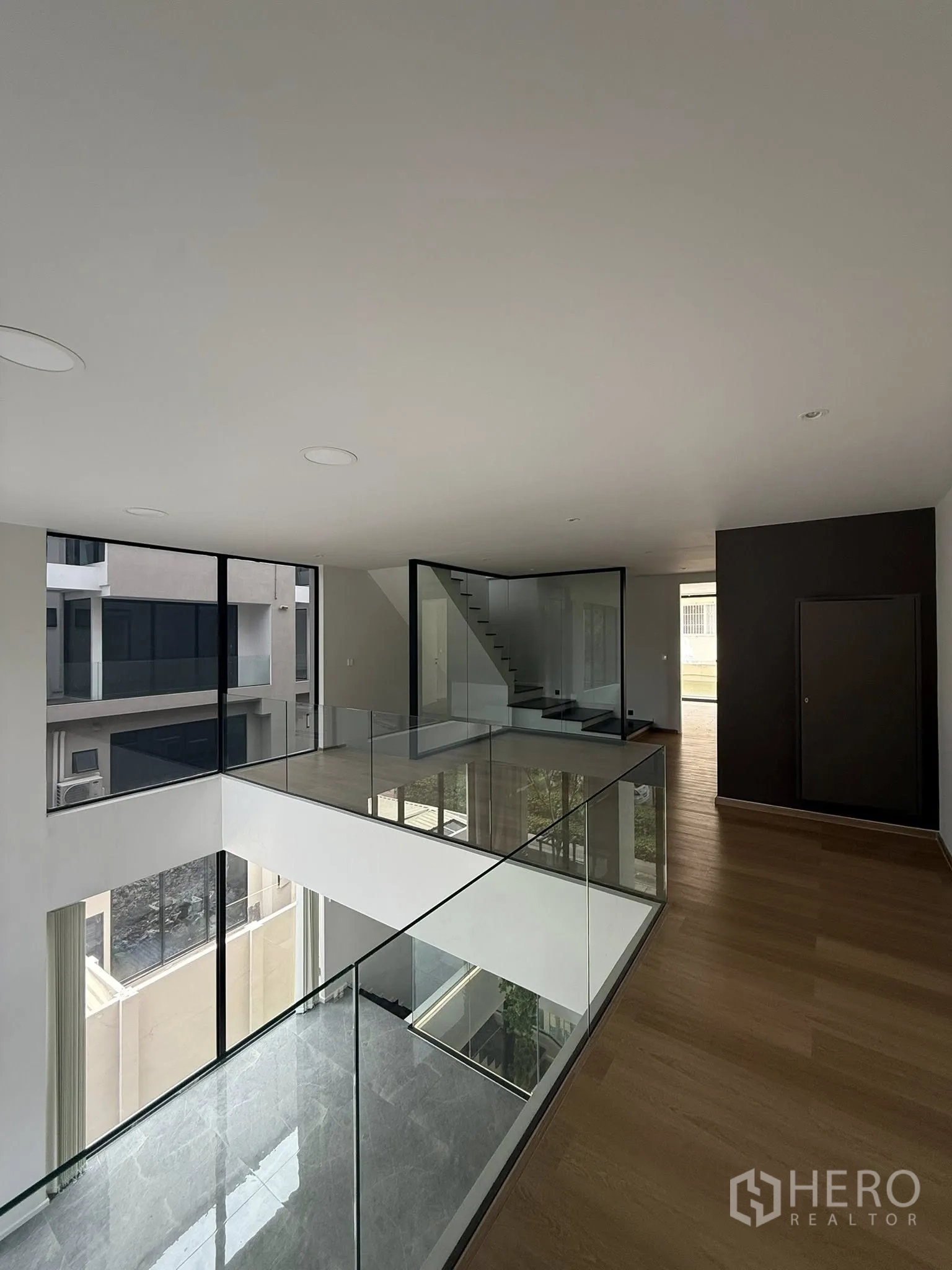 Home Office for rent or sale in Lat Phrao, Bangkok - Upper gallery walkway with glass railings around the central atrium and staircase.