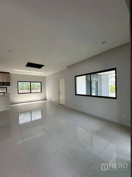 Detached House for sale in Lam Luk Ka, Pathum Thani - Bright open-plan living room with large windows and glossy tiled floor.