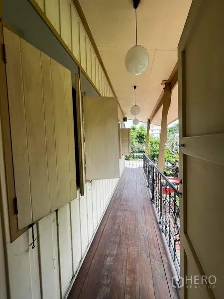 Townhouse for rent - Long covered wooden balcony with railings and hanging globe lights.