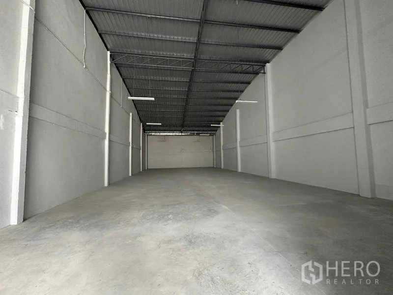 Warehouse for rent in Mueang Samut Sakhon, Samut Sakhon - Wide warehouse interior showing tall white walls, suspended lights, and polished concrete surface.