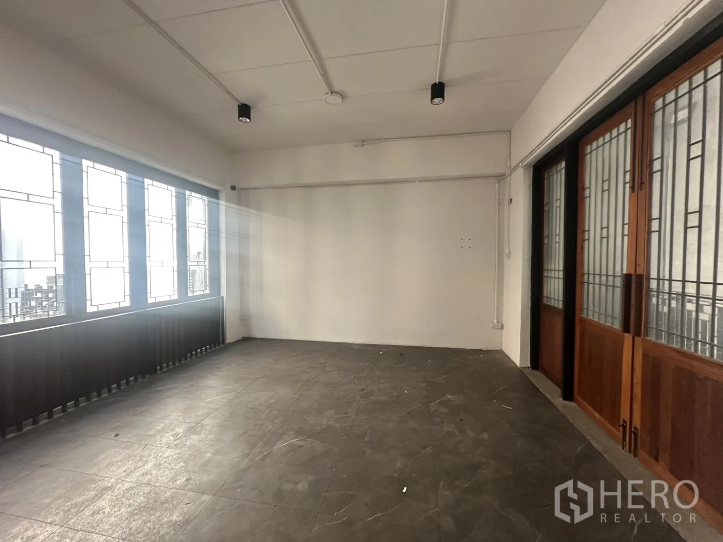 Home Office for rent in Pathum Wan, Bangkok - Upper-floor office room with patterned windows and sliding wooden doors allowing natural light.