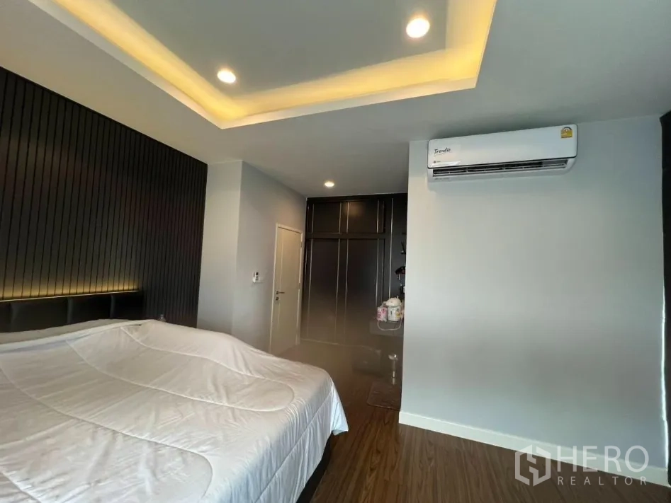 Detached House for rent or sale in Lam Luk Ka, Pathum Thani - Cozy bedroom with tray ceiling lighting, air conditioner, and built‑in wardrobe.