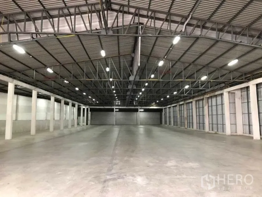 Warehouse for rent in Nonthaburi - Spacious warehouse interior with high steel-truss roof, bright LED lighting, polished concrete floor and multiple roller-shutter loading bays.