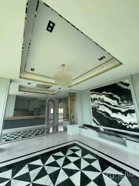 Detached House for sale in Mueang Nonthaburi, Nonthaburi - Grand lounge with chandelier, black‑and‑white marble wall and geometric marble floor leading to open kitchen.