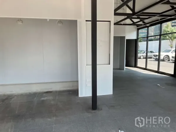 Retail Space for rent - Spacious sales area with white walls, a black column and grey tiled flooring.
