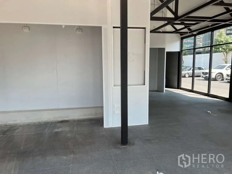 Retail Space for rent - Spacious sales area with white walls, a black column and grey tiled flooring.