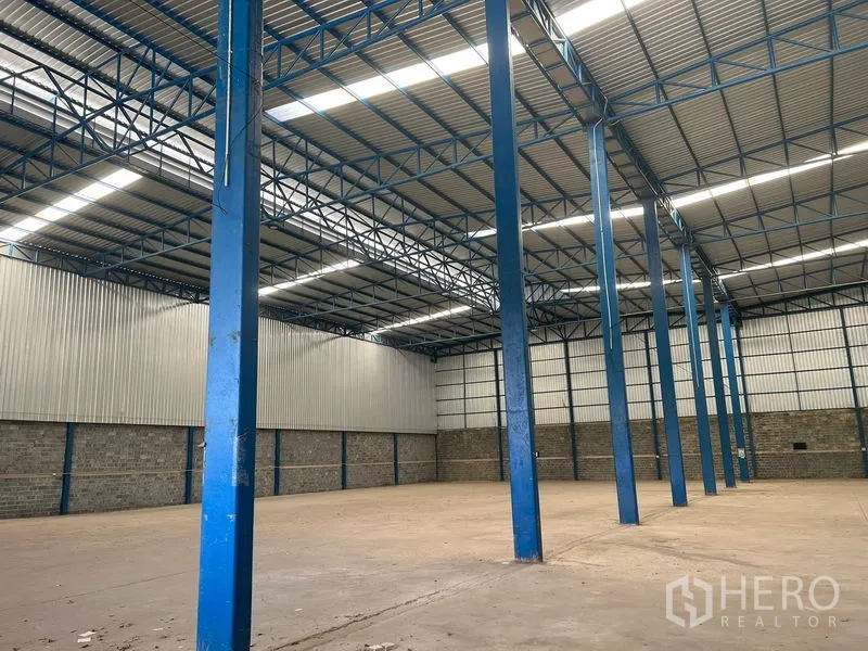 Warehouse for rent in Lat Krabang, Bangkok - Row of blue steel columns and skylights inside an industrial warehouse.