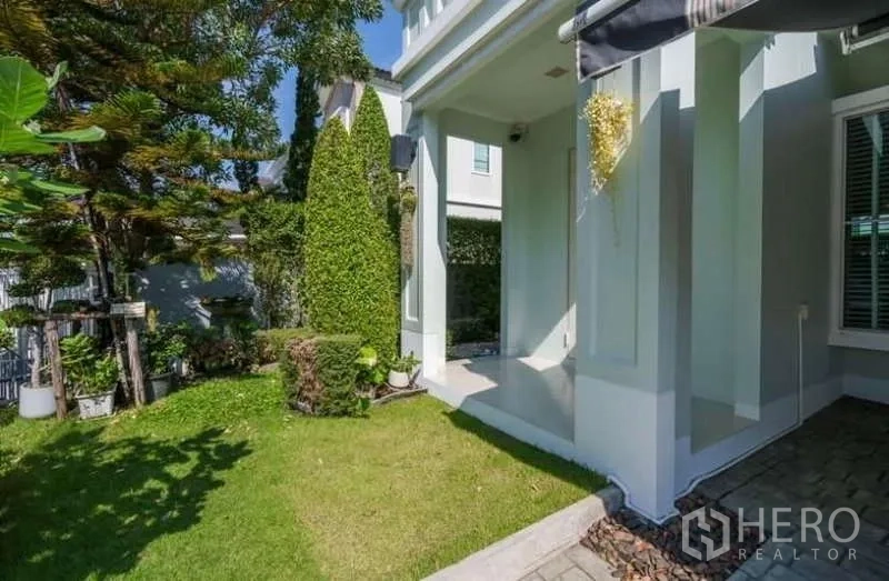 Detached House for rent in Prawet, Bangkok - Landscaped front garden and covered porch with manicured hedges and lawn.