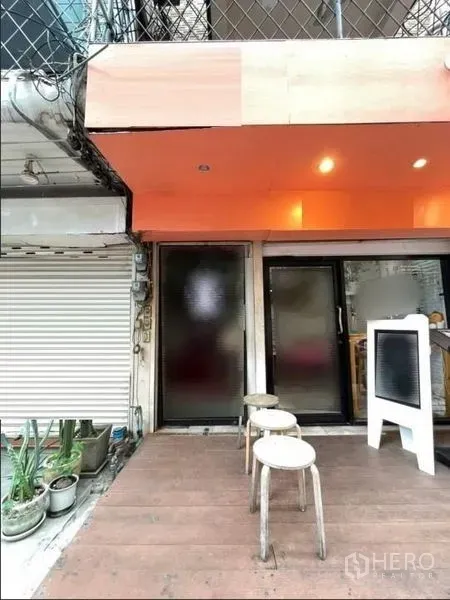 อาคารพาณิชย์ ให้เช่าในPhaya Thai, Bangkok - ทางเข้าชั้นล่างของอาคารพาณิชย์ มีกันสาดสีส้ม ประตูกระจกฝ้า เก้าอี้ และชานไม้.