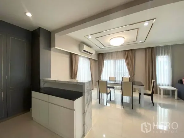 Detached House for rent in Suan Luang, Bangkok - Bright dining area with marble-topped counter, large windows, curtains and recessed ceiling lights.