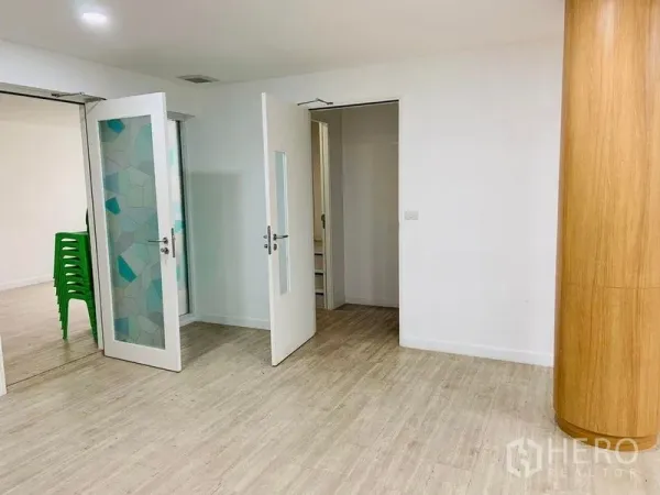 Shophouse for rent or sale in Khlong Toei, Bangkok - Interior corridor with frosted glass double doors, light wood floors and a rounded wooden pillar.