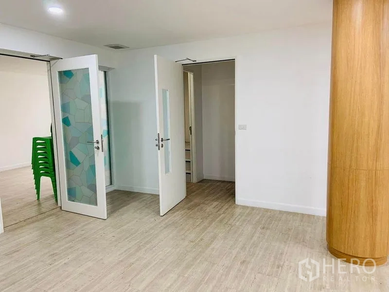 Shophouse for rent or sale in Khlong Toei, Bangkok - Interior corridor with frosted glass double doors, light wood floors and a rounded wooden pillar.