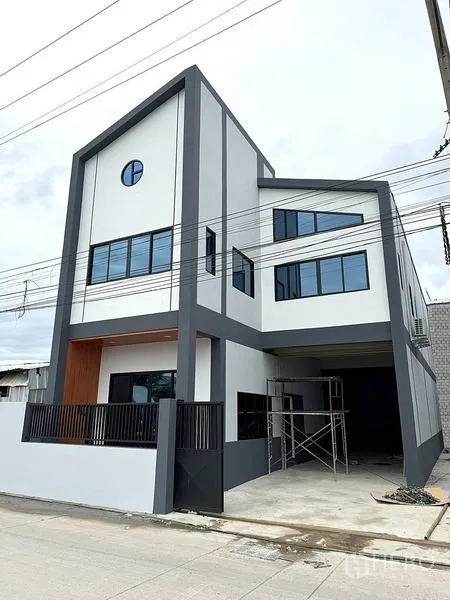 Warehouse for rent in Khlong Luang, Pathum Thani - Contemporary three-storey warehouse facade with gated driveway and large windows.