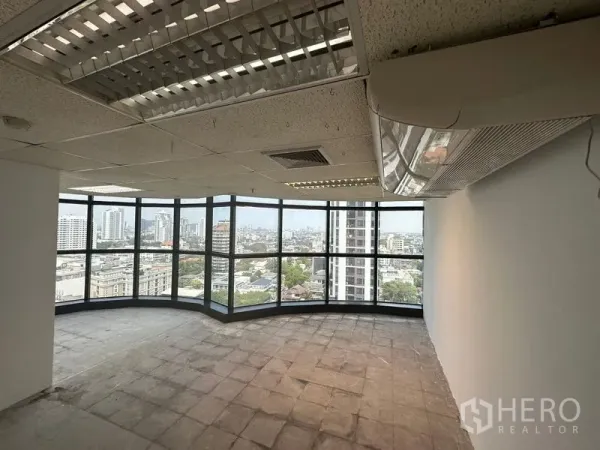 Office Space for rent - Corner office with wraparound floor‑to‑ceiling windows, drop ceiling lights, wall AC, and Bangkok skyline views.