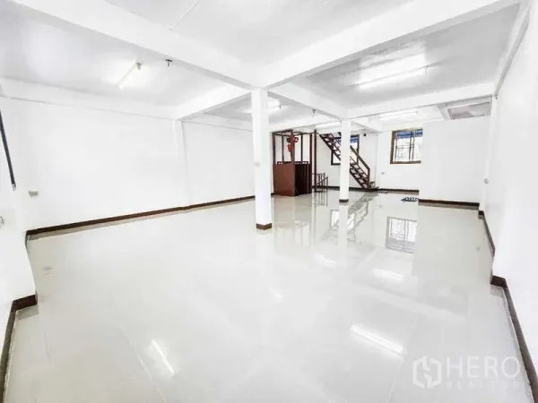 Home Office for rent in Khlong Toei, Bangkok - Expansive white hall with polished tiles and stairs leading to the upper level.