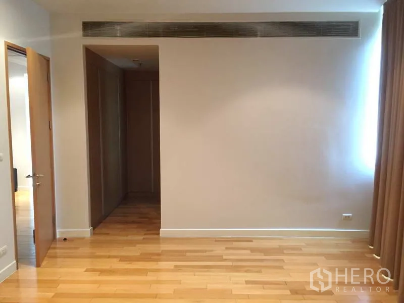 Condominium for sale in Khlong Toei, Bangkok - Spacious bedroom with wood flooring, built-in wardrobe and neutral walls.