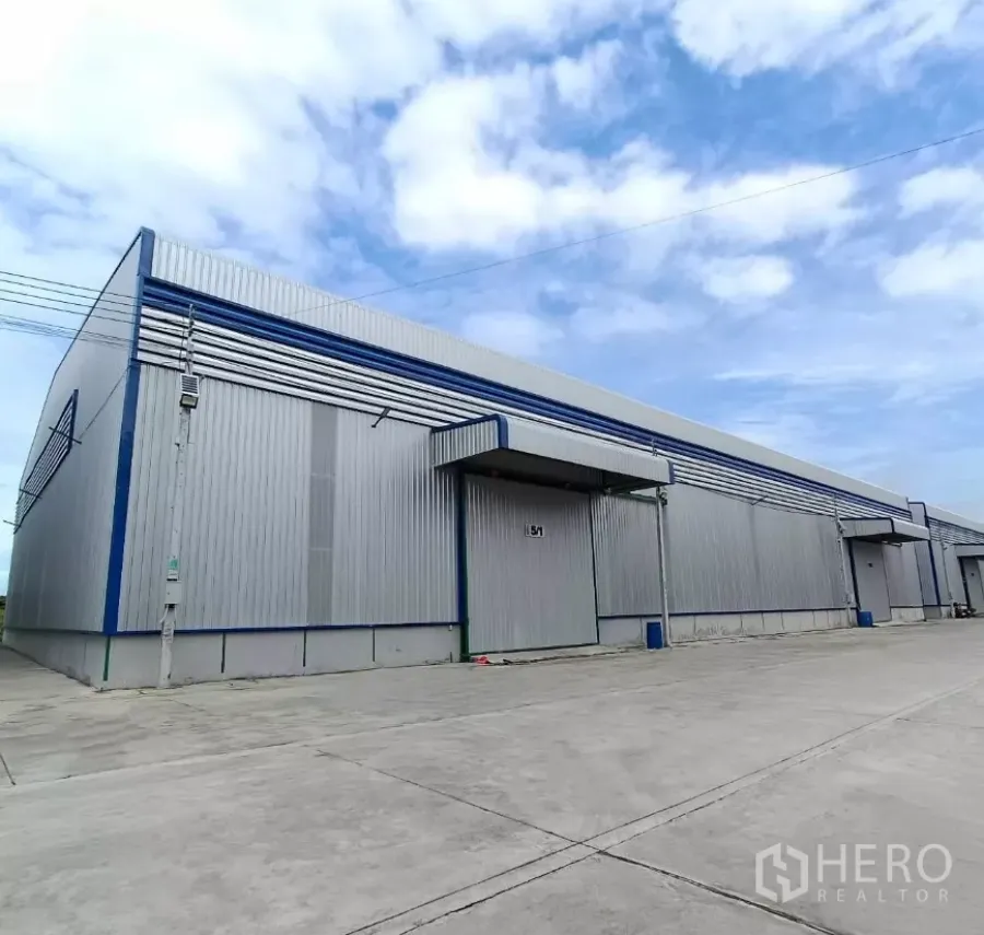 Warehouse for rent in Bang Bon, Bangkok - New metal-clad warehouse exterior in Bang Bon with loading canopies and a wide concrete driveway.