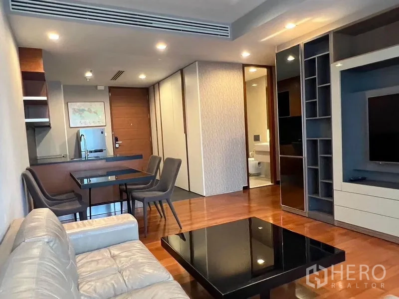 Condominium for rent - Open‑plan living and dining area with dining set, built‑in shelves, and view to compact kitchen and bathroom door.