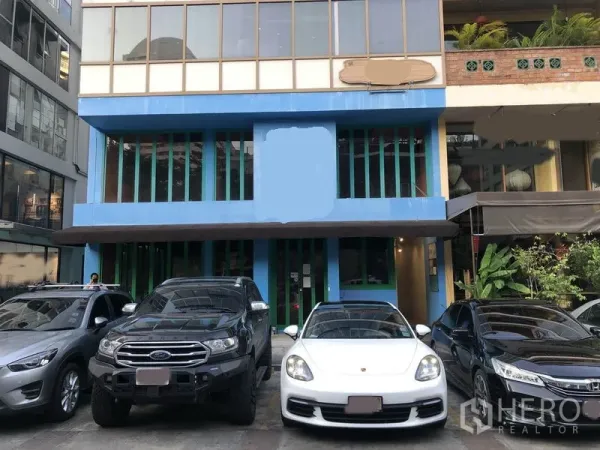 Retail Space for rent in Khlong Toei, Bangkok - Low-rise commercial building facade with glass frontage and on-site parking in front.