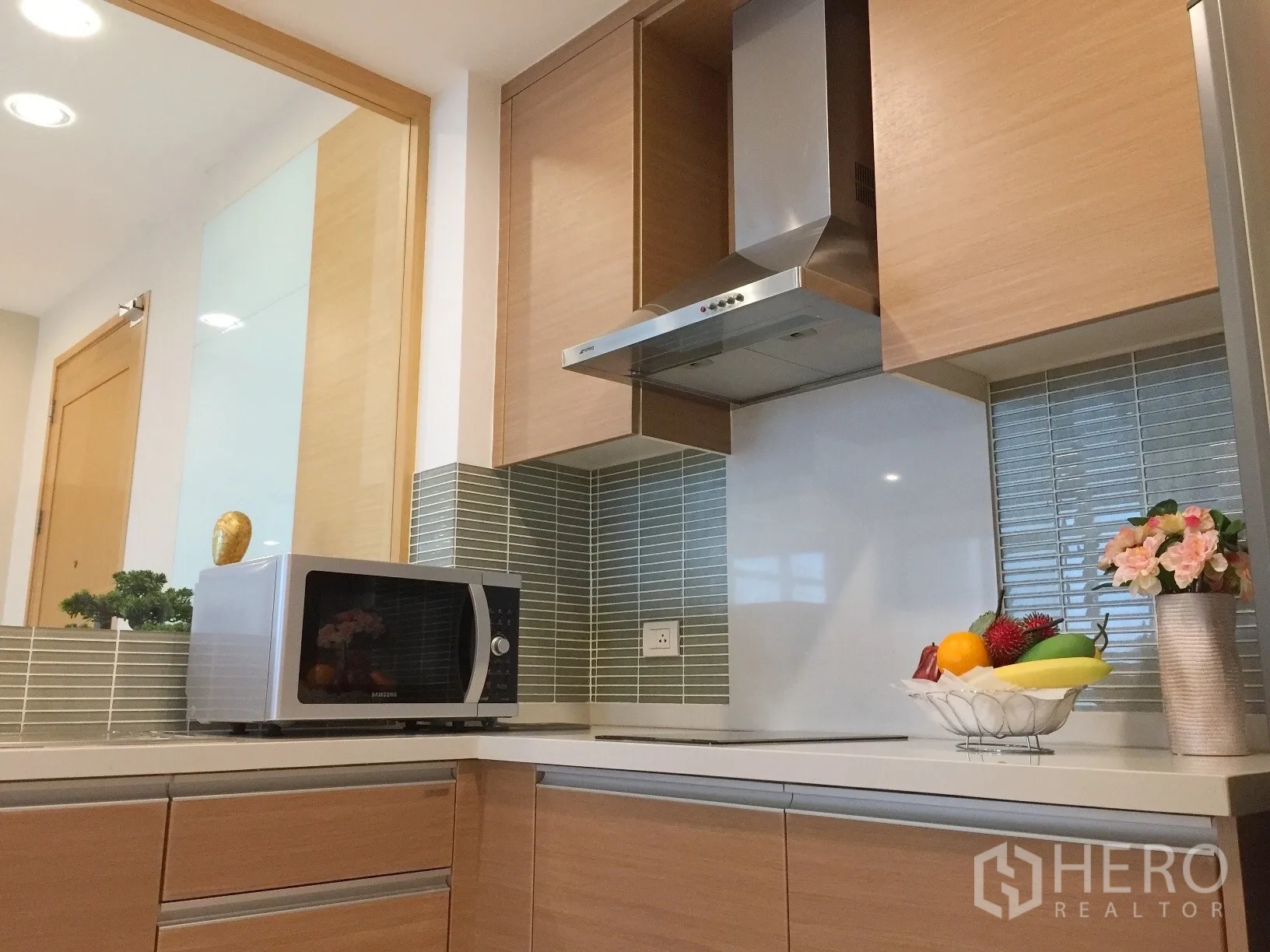 Condominium for rent or sale in Khlong Toei, Bangkok - Fitted kitchen with cabinets, cooktop, hood and microwave.