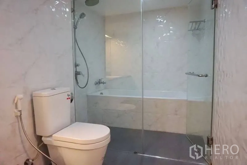 Condominium for rent in Watthana, Bangkok - Contemporary bathroom with glass-enclosed shower, bathtub and white tile walls.