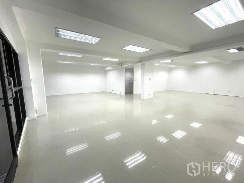 Office Space for rent in Khlong Toei, Bangkok - Large open office area with multiple light panels and a wall of windows.