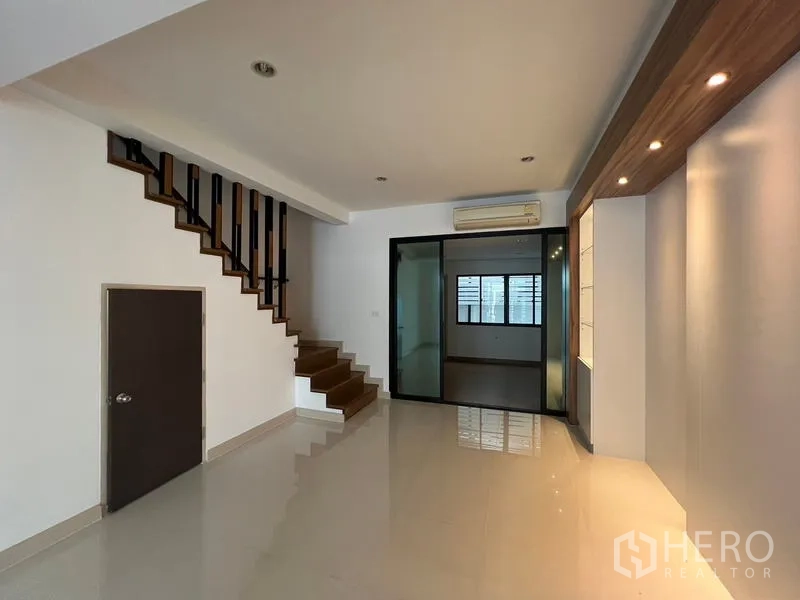 Townhouse for rent or sale in Khlong Toei, Bangkok - Staircase and living area with a glass partition and under-stair storage.