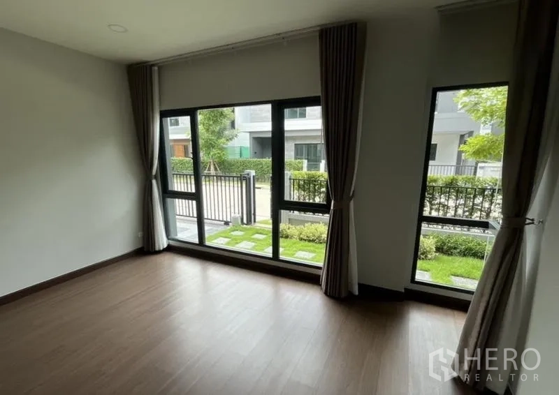 Detached House for rent in Bang Phli, Samut Prakan - Ground-floor room with full-height windows overlooking the garden and front gate.