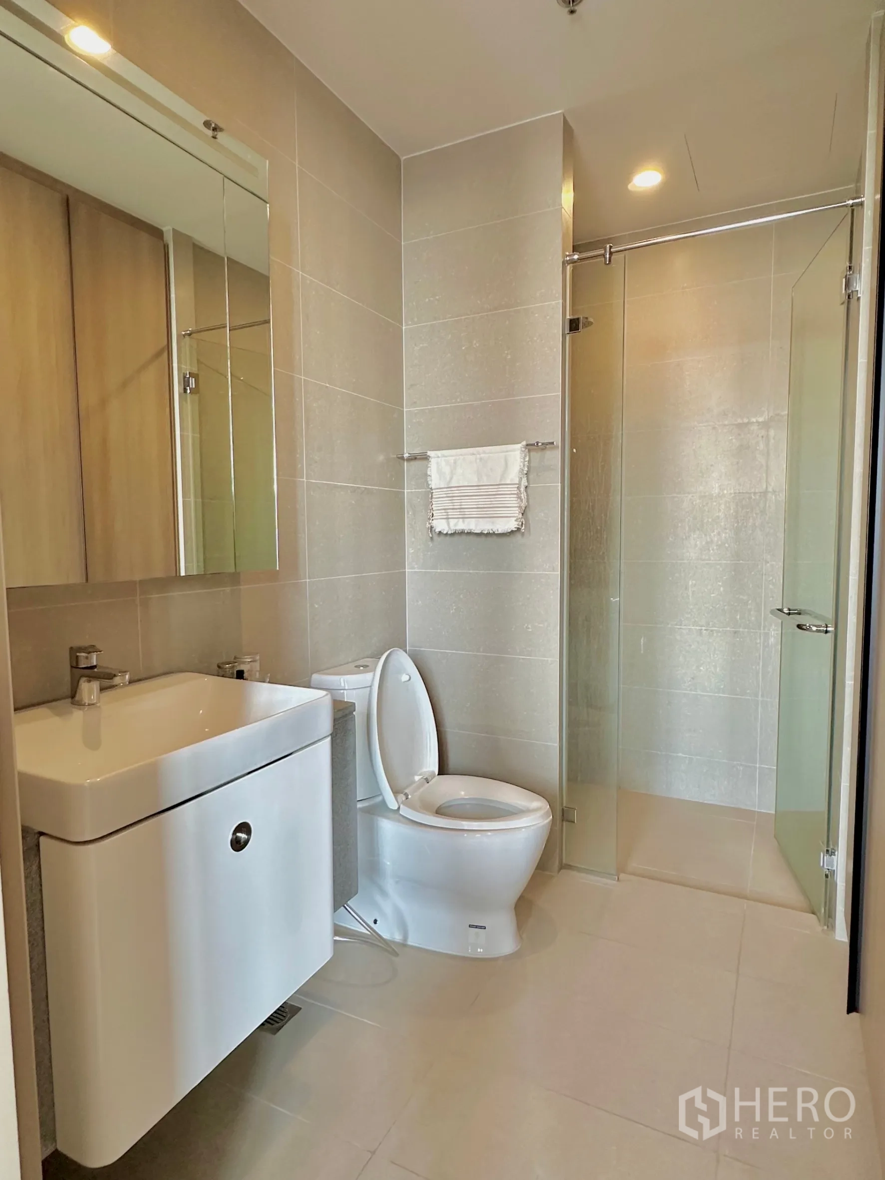 Condominium for rent in Pathum Wan, Bangkok - Contemporary bathroom with vanity, toilet and glass-enclosed shower.