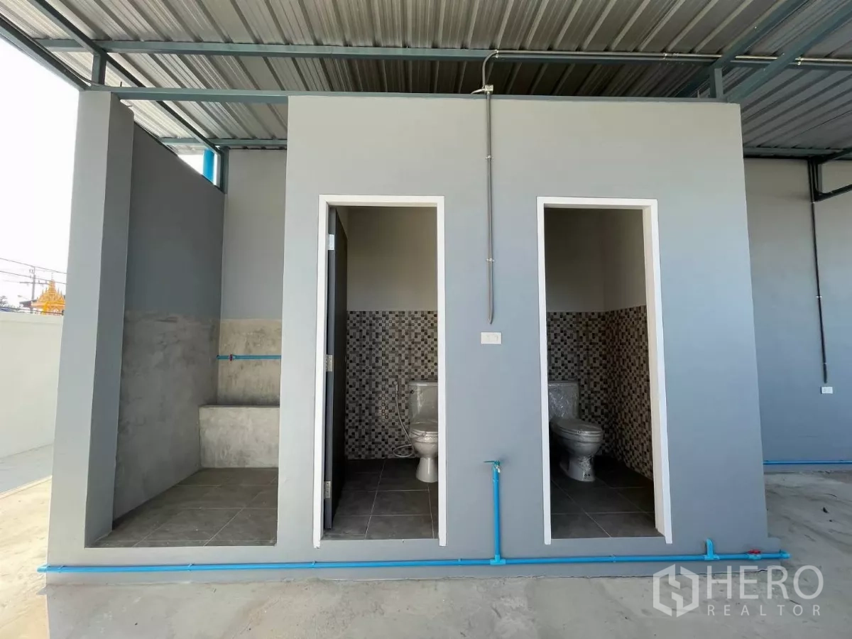 Factory for rent or sale in Bang Phli, Samut Prakan - Covered exterior toilet block with two stalls and a shower area.