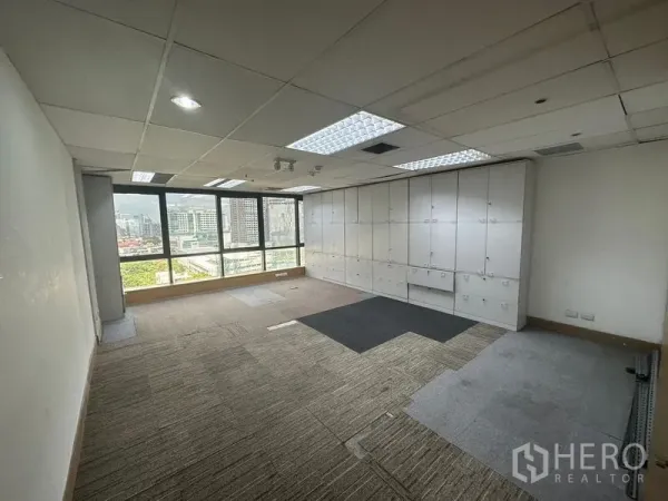 Office Space for rent in Khlong Toei, Bangkok - Workroom with a wall of white storage cabinets and wide windows overlooking the city.