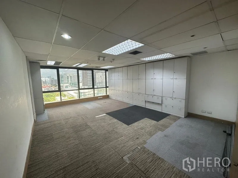 Office Space for rent in Khlong Toei, Bangkok - Workroom with a wall of white storage cabinets and wide windows overlooking the city.
