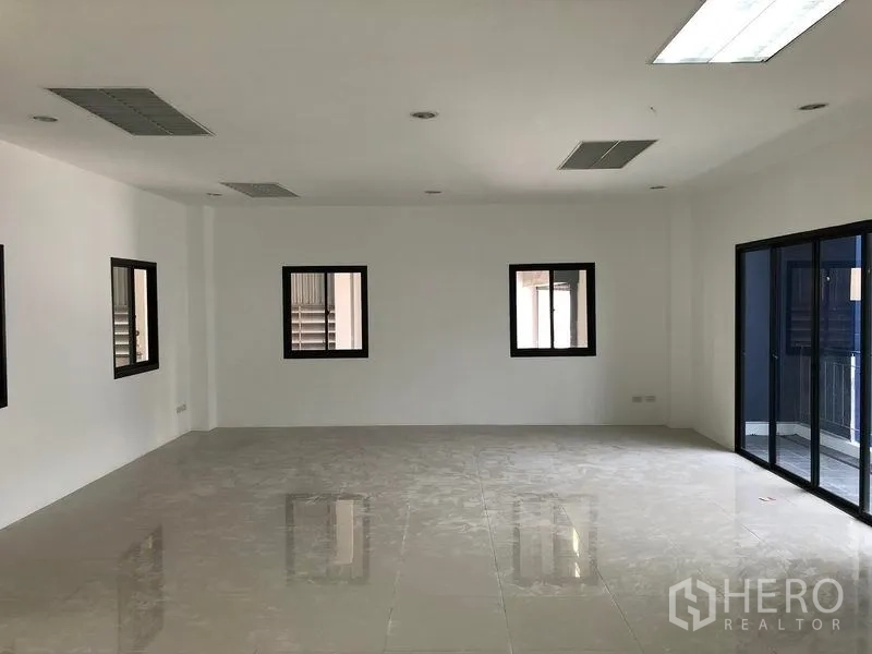 Factory for rent or sale in Samut Prakan - Upper-floor office room with windows and balcony sliding doors overlooking the yard.