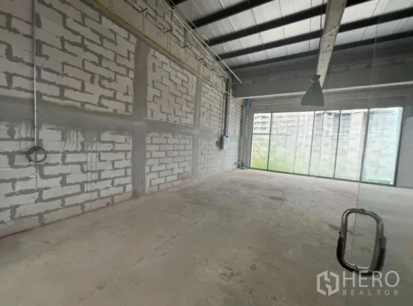 Retail Space for rent - Open-plan shell interior with concrete floor, block walls, exposed services and full-height windows.