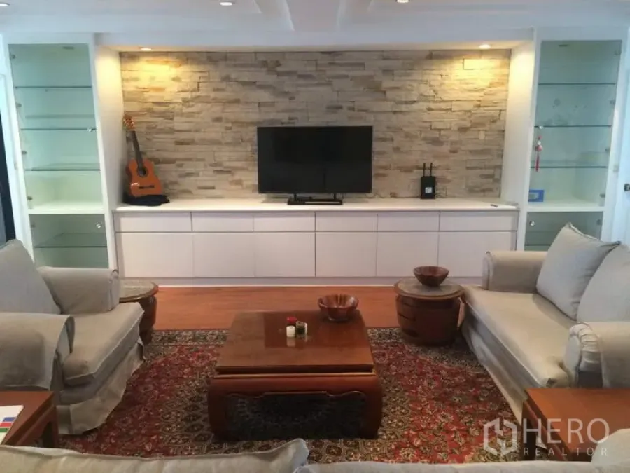 Condominium for rent in Khlong Toei, Bangkok - Spacious living room at President Park condo in Khlong Toei with stone feature wall, built-in TV console, sofas and wooden coffee table.