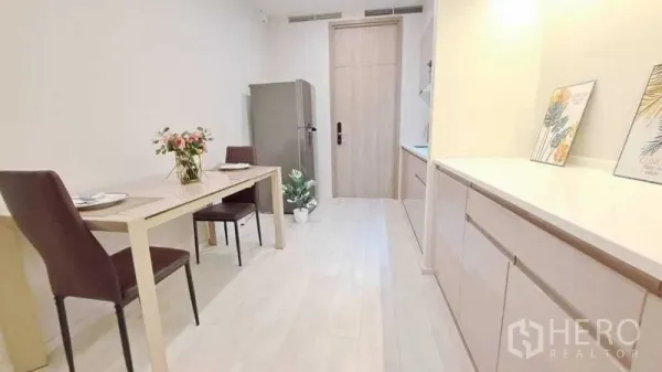 Condominium for rent or sale in Pathum Wan, Bangkok - Dining area with two-seat table beside a long storage counter in a light-toned condo kitchen.