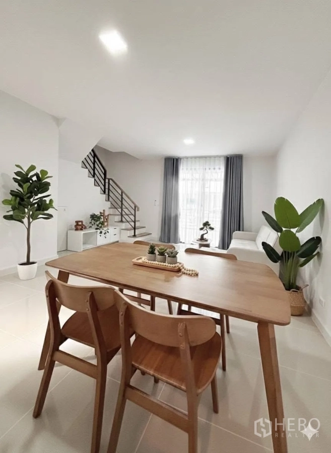 Townhouse for rent in Bang Phli, Samut Prakan - Dining area with wooden table and indoor plants looking toward the living room and staircase.
