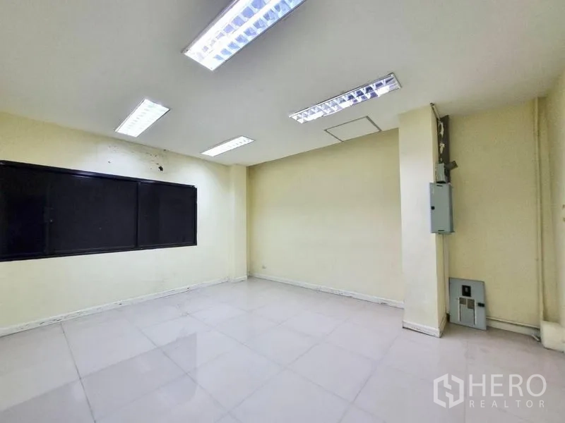 Shophouse for rent in Watthana, Bangkok - Bright office space with tiled flooring, fluorescent lights and an electrical panel.