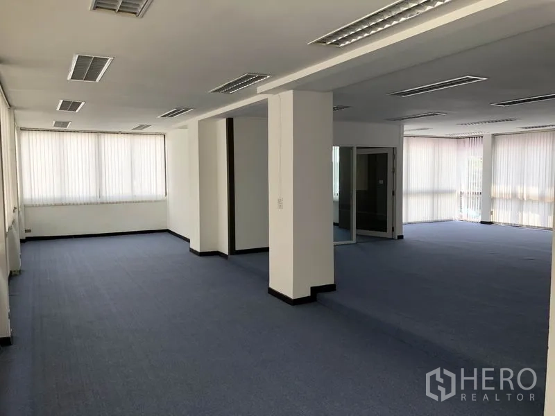 Home Office for rent in Huai Khwang, Bangkok - Large open-plan office level with blue carpet, multiple ceiling lights and structural columns.